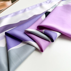 Close-up of abstract geometric silk scarf fabric with smooth satin texture and purple tones