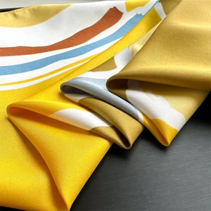 Close-up of luxury twill silk scarf showing vibrant yellow stripes and premium texture
