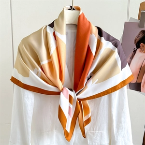 Detail of luxury geometric patterned silk scarf draped over a white linen shirt