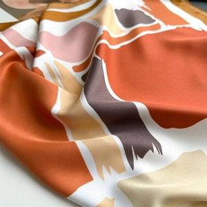 Close-up of luxury silk scarf showing abstract color blocks and soft satin fabric texture