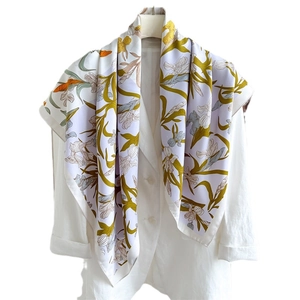 Carré en soie à motif floral élégamment drapé sur un blazer blanc pour un look chic