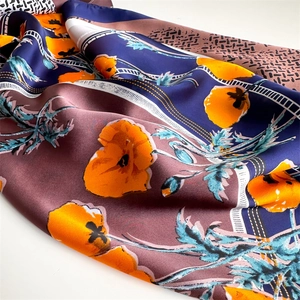 Close-up of silk-feel square scarf with orange floral prints and geometric patterns