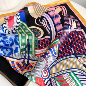 Detail of artistic satin square scarf with abstract geometric patterns and gold stitched edges