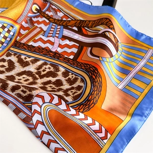 Close-up of silk square scarf showing leopard print details and glossy fabric texture