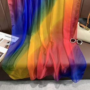 Écharpe en soie dégradé arc-en-ciel drapée sur canapé en cuir avec texture légère