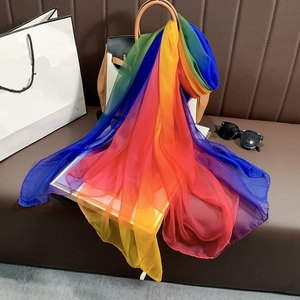 Écharpe en soie dégradé arc-en-ciel drapée sur un sac à main en cuir marron en situation
