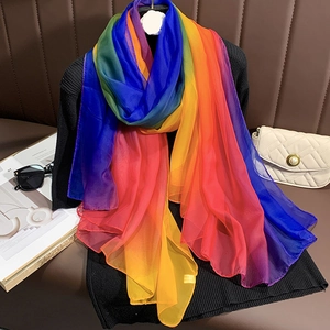 Gros plan d'une écharpe en soie légère dégradé arc-en-ciel sur un pull noir et cuir