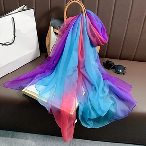 Écharpe en soie dégradée arc-en-ciel pour femmes drapée sur un sac à main en cuir marron