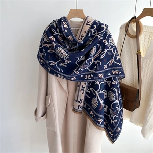 Ethnic floral cashmere-feel scarf with tassels draped on a white wool coat