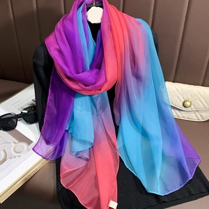 Détail de la texture d'une écharpe en soie dégradé arc-en-ciel sur un pull noir