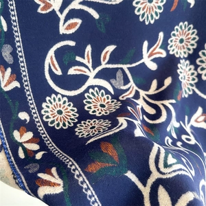 Macro shot of navy blue floral scarf with intricate white daisies and green leaves