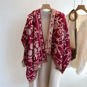 Detail of vintage floral cashmere blend shawl with fringes over a white wool coat