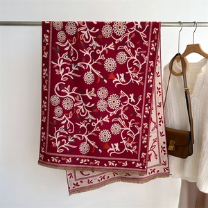 Detail of dark red cashmere-like shawl with intricate floral patterns and fringe edges