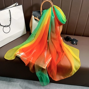 Détail d'un foulard en soie aux couleurs de l'arc-en-ciel drapé sur un sac à main