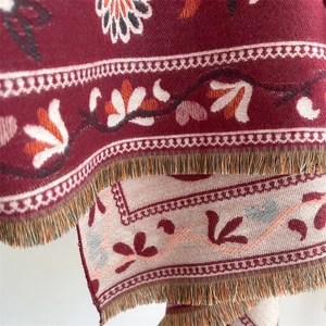 Macro detail of wine red and beige cashmere scarf with floral jacquard and fringe edges