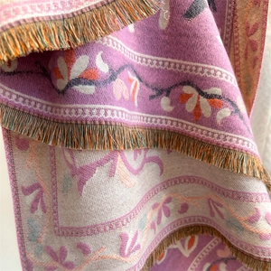 Detail of bohemian floral scarf with intricate tassels and soft cashmere-like texture