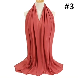Detailed view of the brick red bubble chiffon scarf draped elegantly on a mannequin