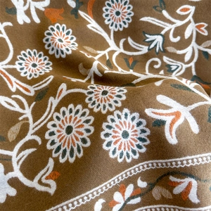 Macro shot of intricate floral embroidery and fine textures on a brown cashmere feel scarf