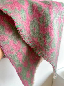 Macro shot of pink and green leopard print knit scarf featuring soft fringe edges