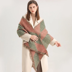 Detail of a thick red and green checkered scarf with tassel edges on a beige coat