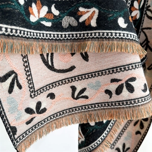 Macro detail of intricate floral embroidery and tassels on the cashmere-like scarf