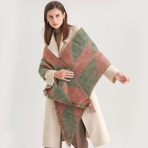 Detail of red and green checkerboard scarf with long fringes worn over a beige coat