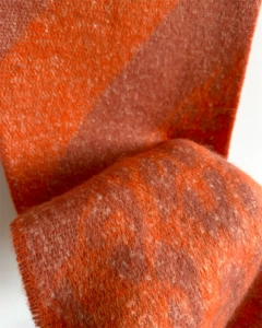 Detailed macro shot of thick orange and brown jacquard knit fabric texture on the scarf