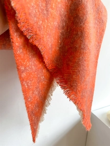 Close-up of thick orange and grey blend wool scarf featuring delicate tassel fringe detail