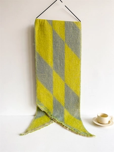 Detail of yellow and grey checkered scarf with fringe hanging on black hanger