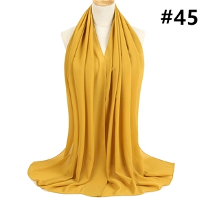 Detail of mustard yellow chiffon hijab scarf with light texture on mannequin