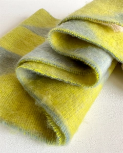 Close-up of yellow and gray checkered scarf with soft faux cashmere texture and fringes