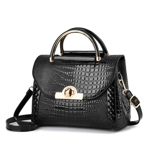 Détail du rabat noir à texture crocodile et du fermoir doré de ce sac à main