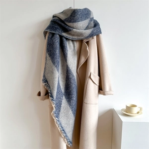 Blue and grey checkered faux cashmere scarf with fringes over a warm beige wool coat
