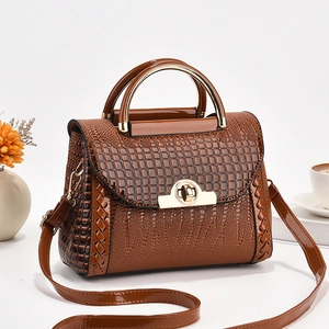 Gros plan sur la texture crocodile marron et le fermoir doré rotatif du sac à main