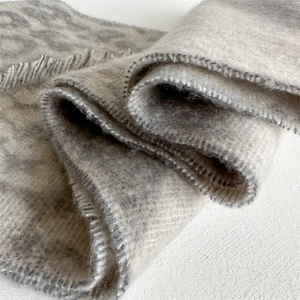 Detailed macro view of gray leopard pattern scarf fabric with soft fringe edges