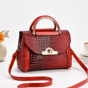 Détail du sac à main rouge motif crocodile avec fermoir doré et poignée ronde élégante