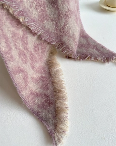 Detailed macro view of the soft knitted texture and delicate fringe edge of the scarf
