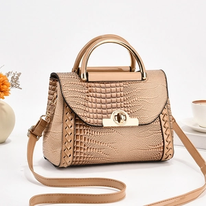 Détail d'un sac à main élégant à motif crocodile avec fermoir doré et accents tressés