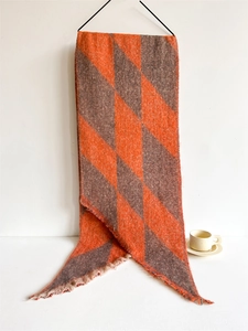 Close-up of thick checkered scarf with fringes in orange and brown cashmere-like fabric