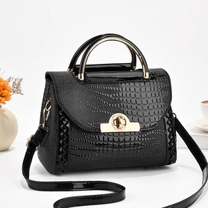 Détail du sac à main noir brillant à motif crocodile avec fermoir doré et anse