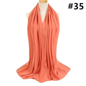 Detail of coral pink chiffon scarf showing elegant pleats and sheer draping texture