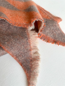 Close-up of thick checkered knit scarf showing frayed edges and orange color-block details
