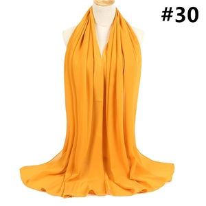 Detailed view of lightweight bright yellow chiffon scarf draped on a white mannequin
