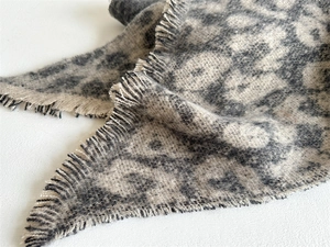 Close-up of soft leopard print scarf featuring long fringes and thick wool-like texture