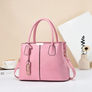 Detail of pink faux leather tote bag showing lychee grain texture and metal ornaments