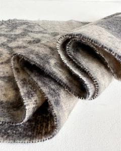 Detail of grey leopard print knit scarf with thick wool-like texture and stitched edges
