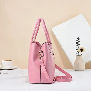 Detailed macro view of a pink faux leather tote bag with gold metal zippers and handles