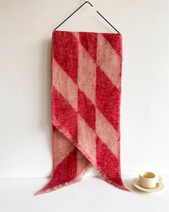 Detailed close-up of red and pink checkered scarf with soft fringed edges and plush texture