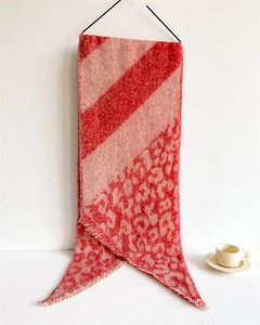 Detail of winter scarf featuring red stripes transition to leopard print with fringed edges