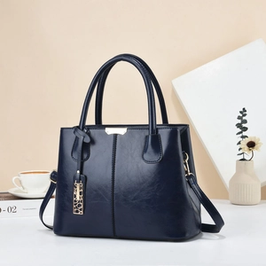 Close-up of dark blue leather handbag with elegant gold hardware and geometric metal tag